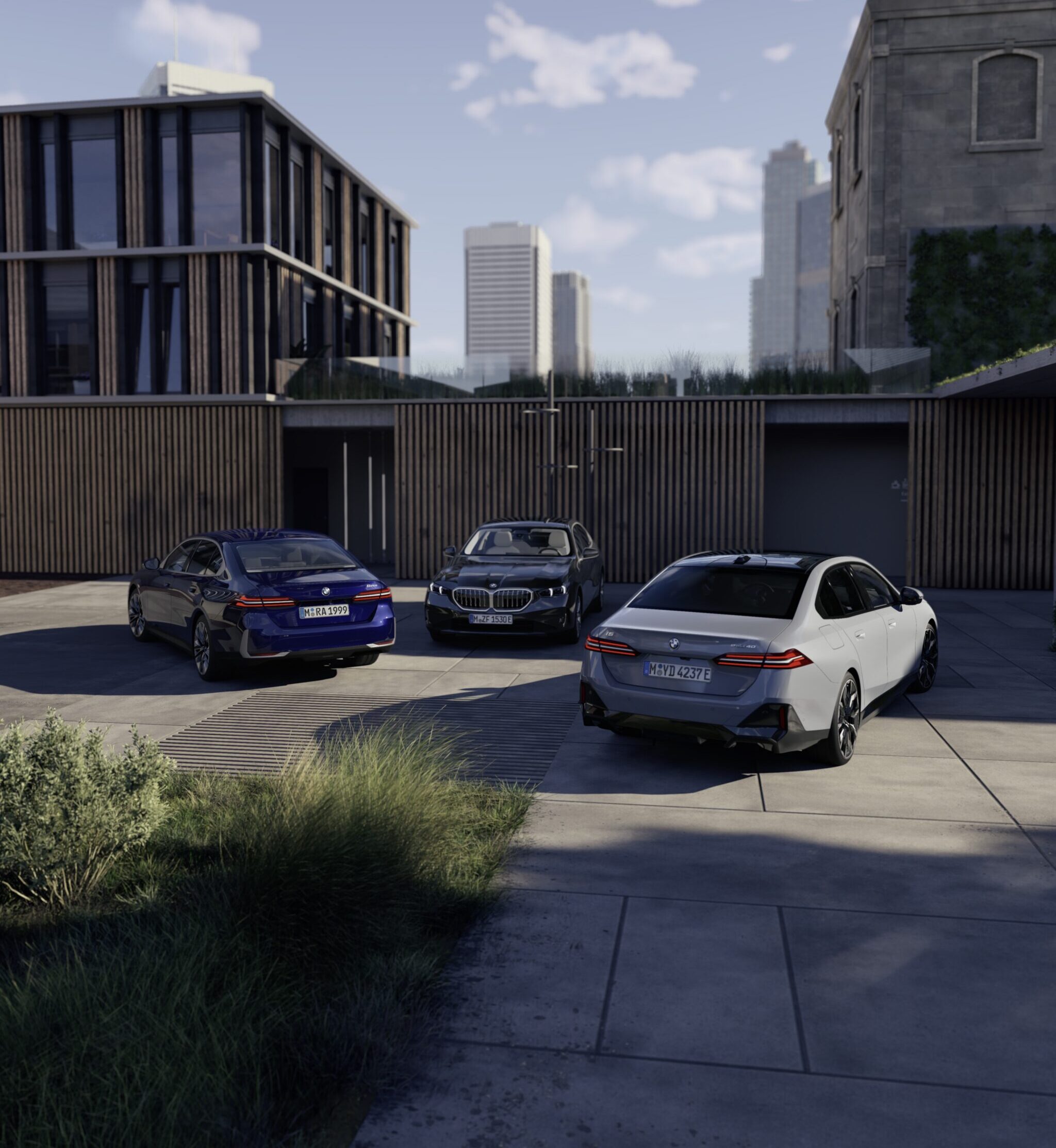 Drei BMW Fahrzeuge stehen in einem Innenhof, drumherum sind Gebäude zu sehen