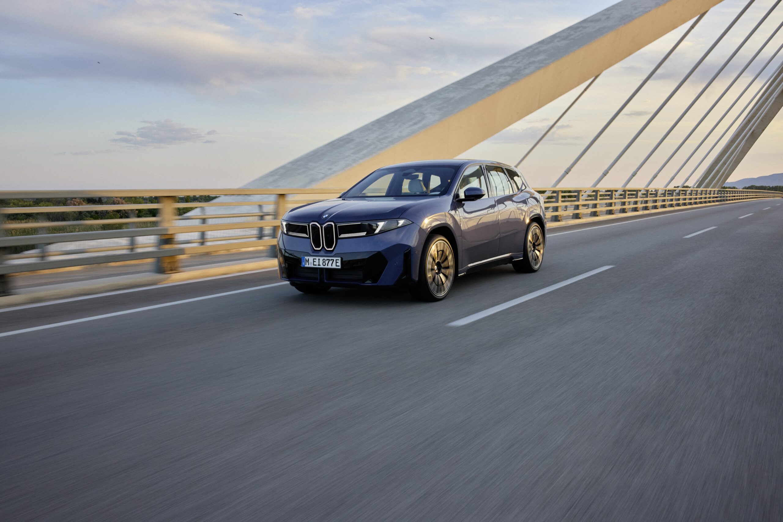 Zu sehen iist der BMW iX3 der Neuen Klasse, wie er &uuml;ber eine Br&uuml;cke f&auml;hrt.