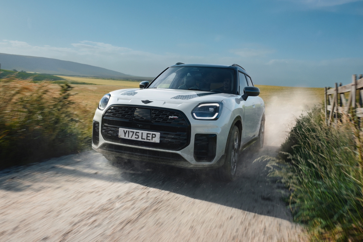 Weißer MINI Countryman fährt auf einer sandigen Straße Richtung Kamera