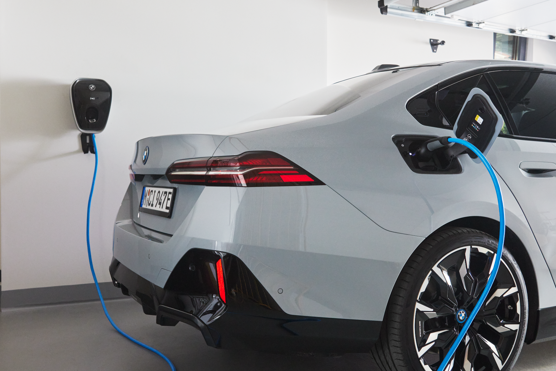Zu sehen ist ein BMW Modell welches grade zuhause in der Garage aufgeladen wird.