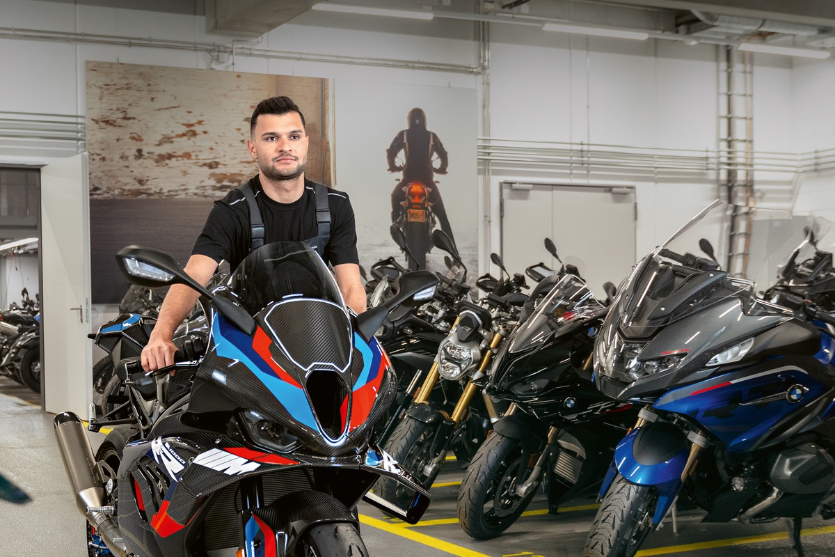 Mann schiebt ein sportliches Motorrad der Marke BMW Motorrad in eine Lagerhalle, in der weitere Motorräder stehen